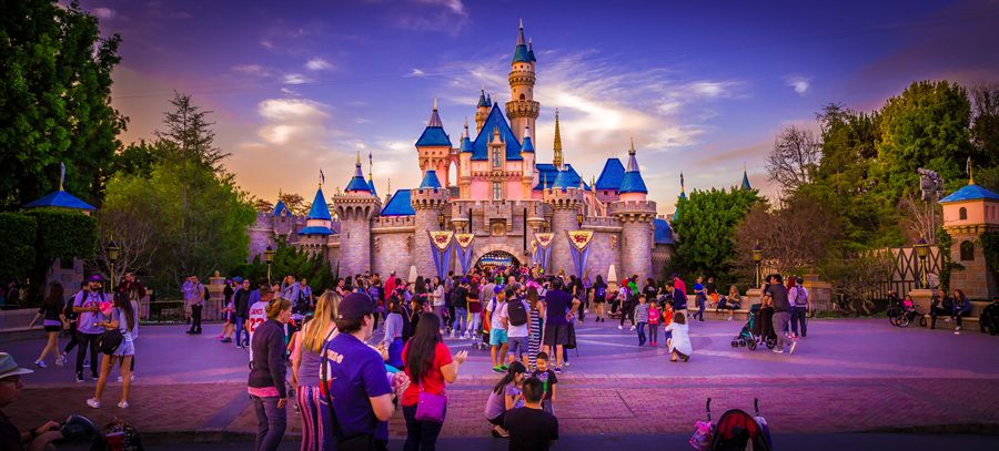 Crowds in front of Sleeping Beauty Castle at Disneyland at dusk
